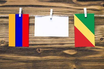 Hanging flags of Armenia and Republic Of The Congo attached to rope with clothes pins with copy space on white note paper on wooden background.Diplomatic relations between countries.