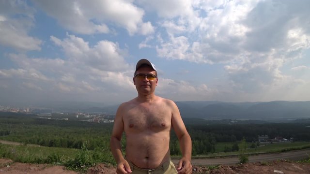 Middle-aged man. Shows Anjali Mudra gesture as a sign of respect and greeting. Points a finger at the viewer interacting with him. Without clothes, glasses, cap. On the mountain. Uncle Sam concept.
