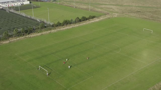 Aerial view, 4K footage, tilt down, Football pitch, Kids playing football on a coastal football field.