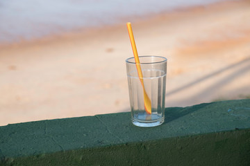 glass cup with straw on green wall at the beach.