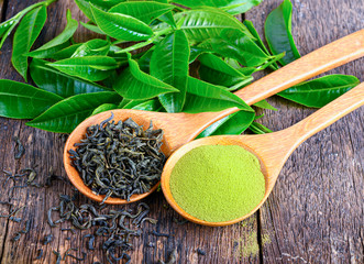 heap of dried green tea leaf and powder on wooden background