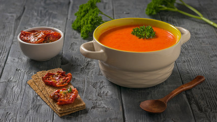 Dried tomatoes and mashed bell pepper soup on a wooden table.
