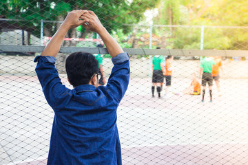 Obraz premium A man looking and cheering futsal competitions at school in sunset time.