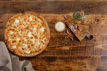 Pizza with salmon and cheese on a wooden background. Ingredients for the sauce. Close-up. The concept of delicious food. View from above.