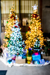 Blur bokeh light of celebration on christmas tree with heap of gift boxes in the room background. Merry Christmas and Happy New Year.