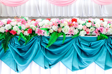 Beautiful of floral arrangement at a wedding ceremony in Thailand. Luxurious wedding arrangement of artificial flowers for wedding ceremony day. Stage decorated with fabric and artificial flowers.