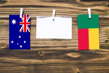 Hanging flags of Australia and Benin attached to rope with clothes pins with copy space on white note paper on wooden background.Diplomatic relations between countries.