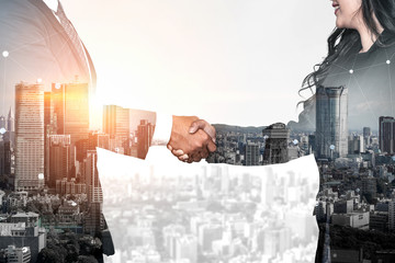 Double exposure image of business people handshake on city office building in background showing...