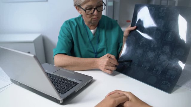 Neurologist showing and explaining to woman brain mri, pov of patient, advices