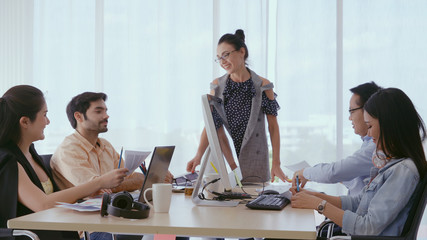 Senior leader giving advice speech to team members. Creative business people meeting at table in modern office. Multicultural business team.