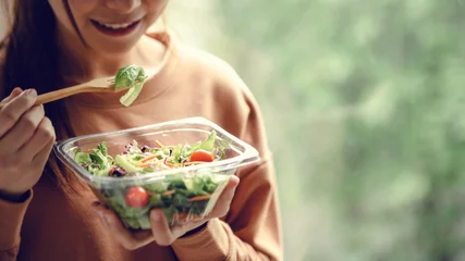 Poster Closeup woman eating healthy food salad, focus on salad and fork. © oatawa