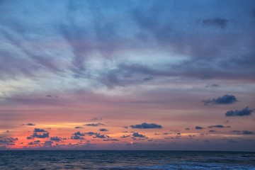 Phuket beach sunset, colorful cloudy twilight sky reflecting on the sand gazing at the Indian Ocean, Thailand, Asia.