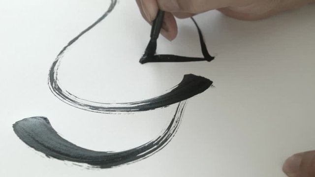 CU of hand drawing strokes of calligraphy on white paper.
