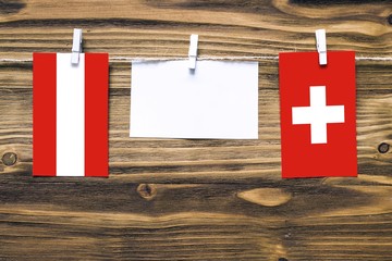 Hanging flags of Austria and Switzerland attached to rope with clothes pins with copy space on...