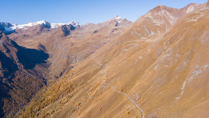 Road to the Gavia mountain pass in Italy. Amazing aerial view of the mountain bends creating beautiful shapes. Fall time. Warm colors. Nobody on the road