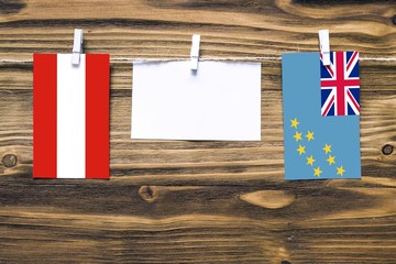 Hanging flags of Austria and Tuvalu attached to rope with clothes pins with copy space on white...