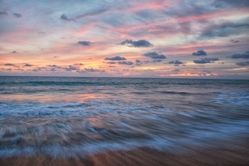 Phuket beach sunset, colorful cloudy twilight sky reflecting on the sand gazing at the Indian Ocean, Thailand, Asia.