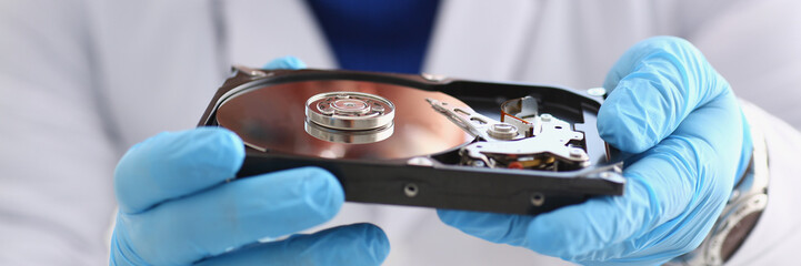 male repairman wearing blue gloves is holding a hard drive