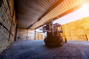 Fototapeta na wymiar Forklift loader load lumber into a dry kiln. Wood drying in containers.