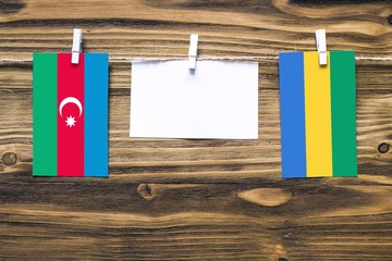 Hanging flags of Azerbaijan and Gabon attached to rope with clothes pins with copy space on white...