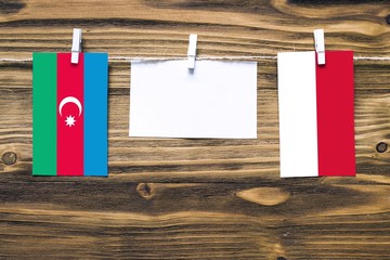 Hanging flags of Azerbaijan and Indonesia attached to rope with clothes pins with copy space on white note paper on wooden background.Diplomatic relations between countries.