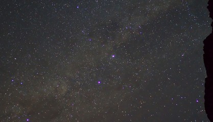 Stars on night sky with shadow of cliff