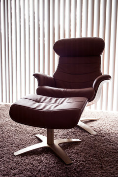 Classic, modern chair with ottoman in a low lit room