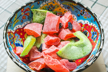 Pressed dried fruit from red papaya and green kiwi in deep plate on table.