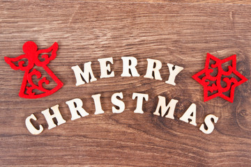 Inscription Merry Christmas with red decorations on rustic board, festive time concept