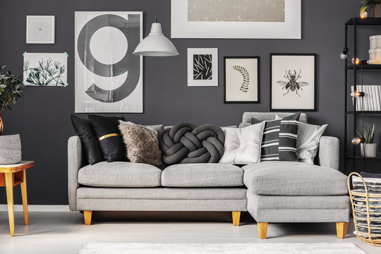 Grey and black pillows on comfortable corner sofa in fashionable scandinavian living room