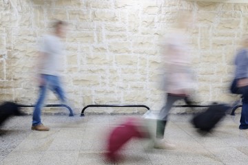 Plakat blurred passengers with trolley at the airport