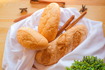 Freshly baked delicious bread on wooden table with white cloth