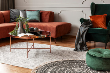 Brown comfortable corner sofa in elegant living room interior with grey wall with molding and coffee table with flowers