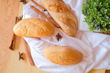 Freshly baked delicious bread on wooden table with white cloth