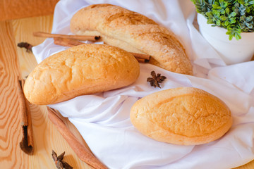 Freshly baked delicious bread on wooden table with white cloth