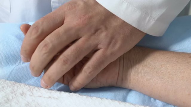 Doctor touching unconscious patient hand after surgery, checking pulse, aid
