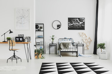 Black and white interior design of bright kid's bedroom with laptop on wooden desk