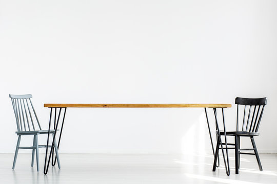 White Room With Two Chairs At A Long Wooden Table, Real Photo With Copy Space On Empty Wall