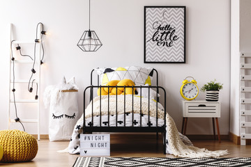 Yellow knot pillow on single metal bed in bright bedroom interior with white scandinavian ladder,...