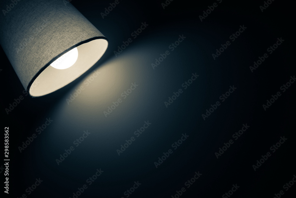 Wall mural dark and vintage mood of a desk lamp shining warm light in the dark room in black and blue tone with