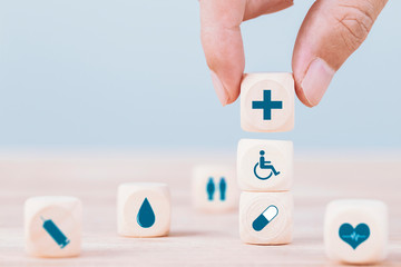Hand chooses a emoticon icons healthcare medical symbol on wooden block , Healthcare and medical...