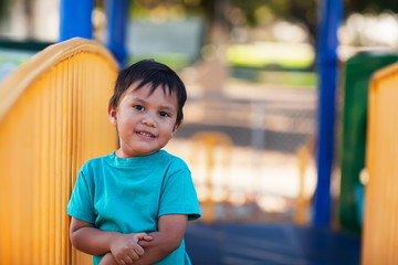 A cute little boy holding on to his arm after an injury at a kids playground.