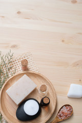 Flat lay Spa composition with body care items on wood background. Sea salt in bowl, towels, scrub, aroma oil in bottles and flowers.