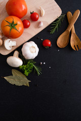 spices herbs and greens. Ingredients for cooking. Food background on black slate table. Top view copy space. Rosemary, tomatoes, garlic and peppers. - Image