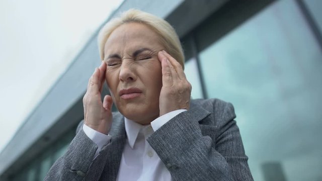 Female company head in eyeglasses feeling strong teeth pain, dental problems