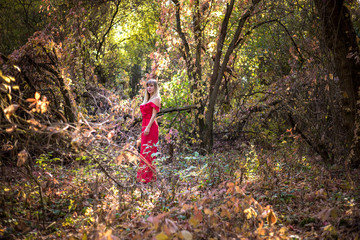 Beautiful elf girl in red dress in the autumn forest. forest fantasy fairy tale