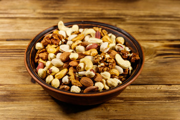 Mixed nuts on wooden table. Walnuts, pistachio, almond, peanut, cashew, hazelnut in ceramic bowl. Healthy eating concept