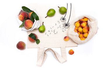 Fruits pears, peaches, apricots, pears in eco bags on a white background. Zero waste concept.