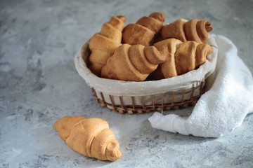 Fresh croissants are in the breadbox on the table. Bakery. Close-up, minimalism. Tasty breakfast. - obrazy, fototapety, plakaty