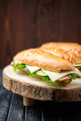 Hunter's sandwich with ham, cucumber, cheddar cheese on wooden board